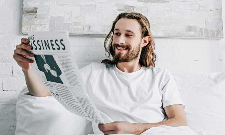 Früh aufstehen, Mann im Bett liest Business Zeitung