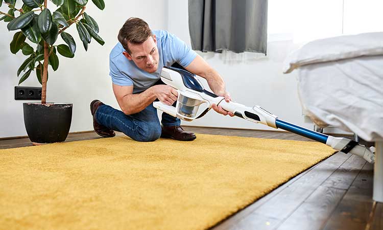 vacuum under bed, man vacuum under bed at right angle